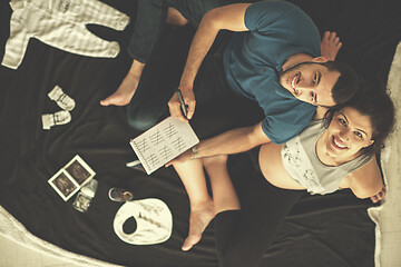 Image showing top view of couple checking a list of things for their unborn ba