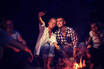 Image showing young friends relaxing around campfire