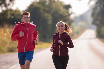 Image showing young couple jogging along a country road