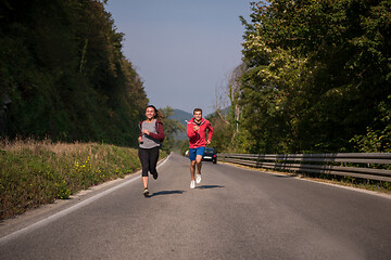 Image showing young couple jogging along a country road