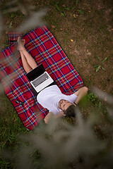 Image showing top view of man using a laptop computer under the tree