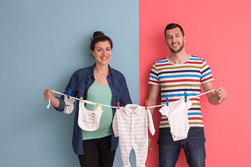 Image showing young couple holding baby bodysuits