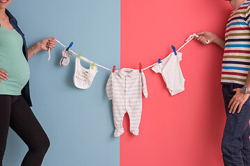 Image showing young couple holding baby bodysuits