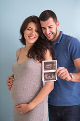 Image showing couple looking ultrasound picture isolated on blue background