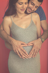 Image showing pregnant  couple showing heart with their hands