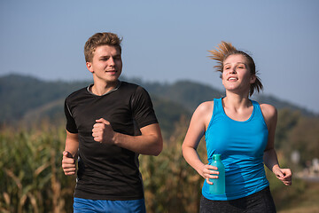 Image showing young couple jogging along a country road