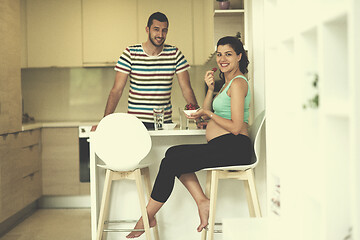 Image showing couple eating fruit strawberries at kitchen