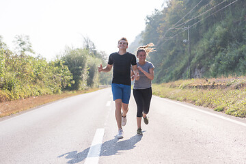 Image showing young couple jogging along a country road