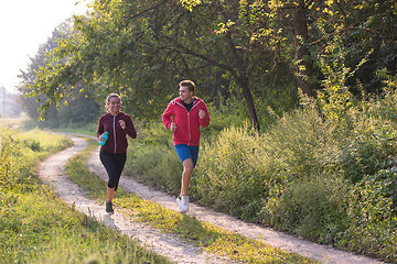 Image showing young couple jogging along a country road