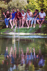 Image showing friends enjoying watermelon while sitting on the wooden bridge