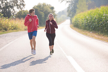 Image showing young couple jogging along a country road