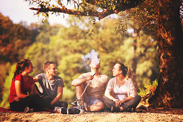 Image showing friends smoking hookah on the river bank