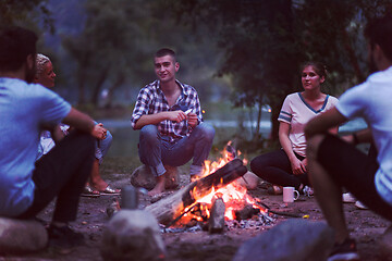 Image showing young friends relaxing around campfire