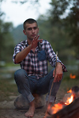 Image showing young friends relaxing around campfire