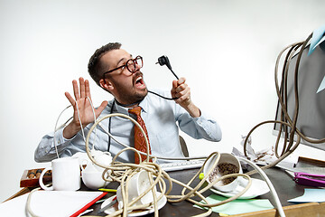 Image showing Young man tangled in wires on the workplace