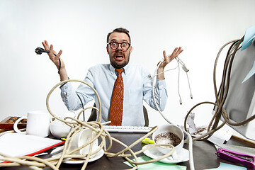 Image showing Young man tangled in wires on the workplace