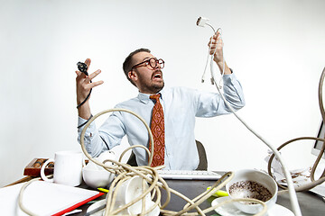 Image showing Young man tangled in wires on the workplace