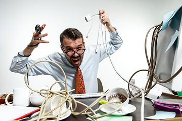 Image showing Young man tangled in wires on the workplace