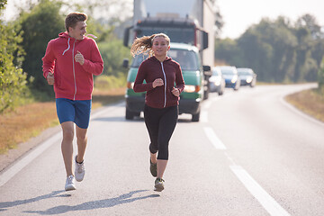 Image showing young couple jogging along a country road