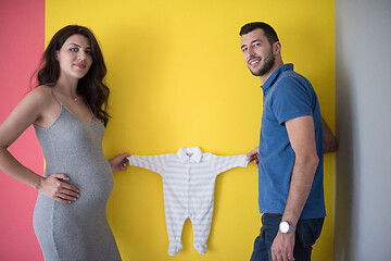 Image showing young couple holding baby bodysuits