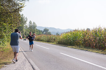 Image showing videographer recording while couple jogging along a country road