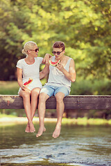 Image showing couple enjoying watermelon while sitting on the wooden bridge