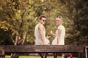 Image showing couple enjoying watermelon while sitting on the wooden bridge