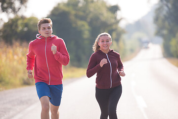 Image showing young couple jogging along a country road