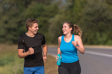 Image showing young couple jogging along a country road