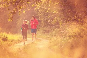 Image showing young couple jogging along a country road