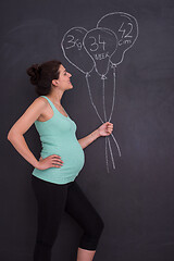 Image showing Portrait of pregnant woman in front of black chalkboard