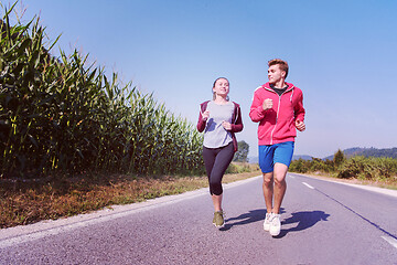 Image showing young couple jogging along a country road