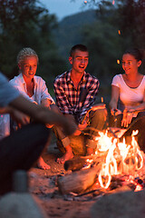 Image showing young friends relaxing around campfire