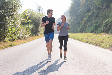 Image showing young couple jogging along a country road