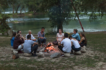 Image showing young friends relaxing around campfire