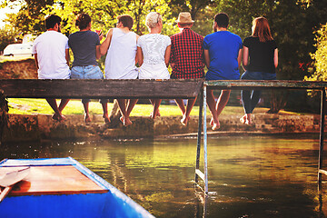 Image showing rear view of friends enjoying watermelon while sitting on the wo