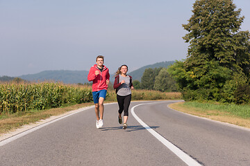 Image showing young couple jogging along a country road