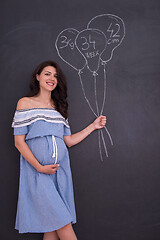 Image showing Portrait of pregnant woman in front of black chalkboard