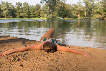 Image showing girl in a green bikini relaxing on the riverbank