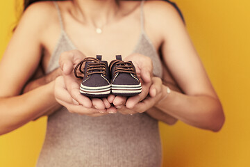 Image showing couple holding newborn baby shoes