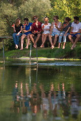 Image showing friends enjoying watermelon while sitting on the wooden bridge