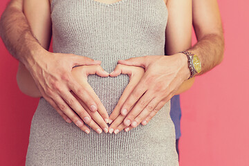 Image showing pregnant  couple showing heart with their hands