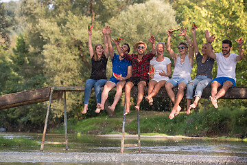 Image showing friends enjoying watermelon while sitting on the wooden bridge