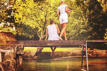 Image showing couple enjoying watermelon while sitting on the wooden bridge