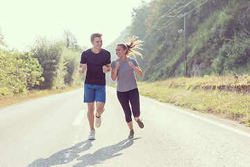 Image showing young couple jogging along a country road