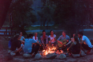 Image showing young friends relaxing around campfire