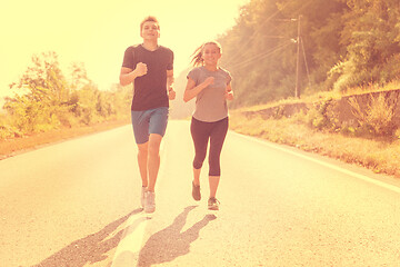 Image showing young couple jogging along a country road