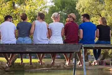 Image showing rear view of friends enjoying watermelon while sitting on the wo