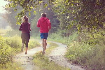 Image showing young couple jogging along a country road