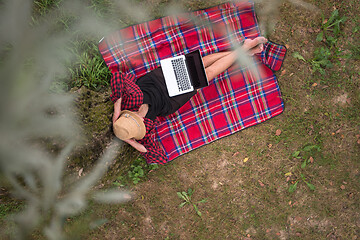 Image showing top view of man using a laptop computer under the tree